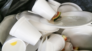 A close-up of used styrofoam cups and plates in a garbage can