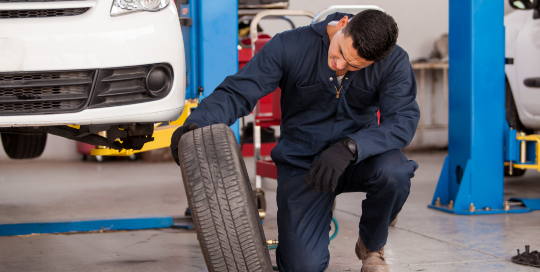 Repair technician changing old tire in service bay